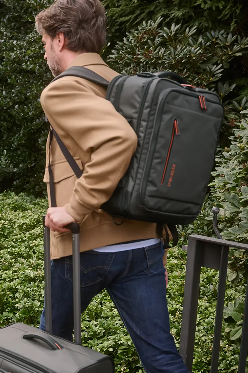 Moderner Reiserucksack in Schwarz mit orangenen Akzenten für Business und Freizeit Mann mit schwarzem Rucksack und Trolley, unterwegs im Freien, perfekt für Reisen und Geschäftsreisen