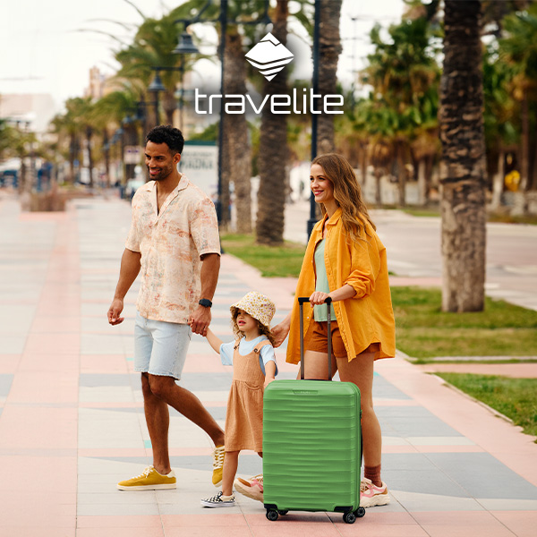 Familie beim Spaziergang mit Travelite-Koffer an der Promenade Familie spaziert an einer sonnigen Promenade, trägt sommerliche Kleidung und zieht einen grünen Travelite-Koffer hinter sich her