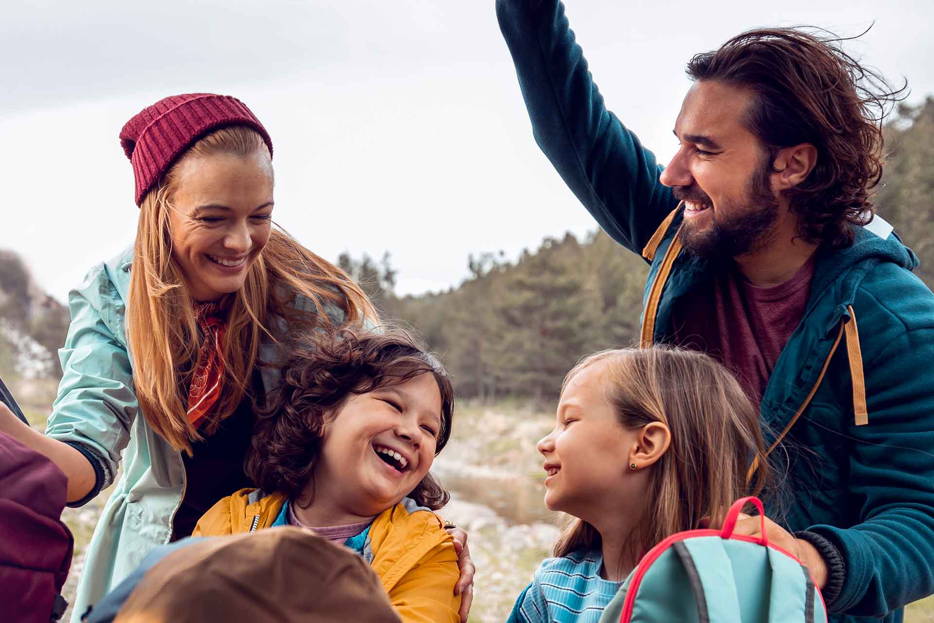 Glückliche Familie beim Wandern in der Natur Eine fröhliche Familie mit zwei Kindern lacht im Freien während einer Wanderung