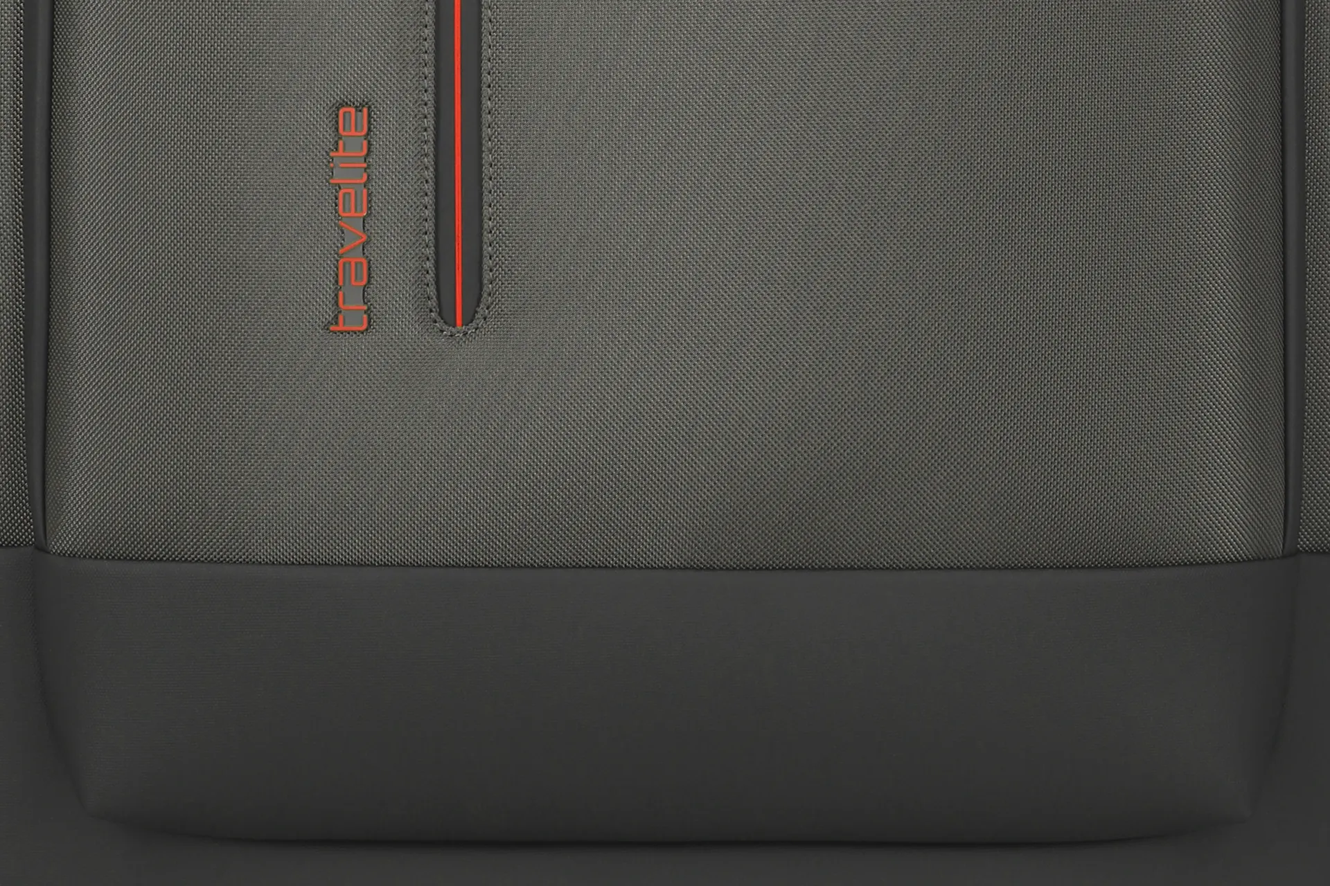 Detailansicht eines grauen Travelite Rucksacks mit rotem Reißverschluss und Logo Nahaufnahme des unteren Teils eines grauen Travelite Rucksacks mit auffälligem roten Reißverschluss und Travelite-Logo