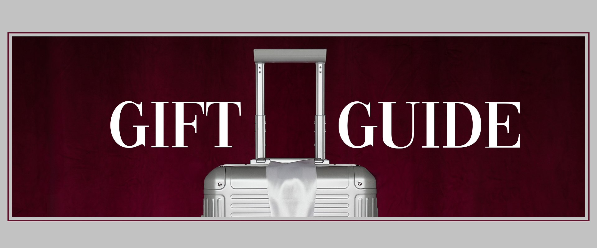 Geschenkführer: Eleganter Koffer mit rotem Hintergrund Silberner Koffer vor rotem Hintergrund mit dem Text 'Gift Guide'
