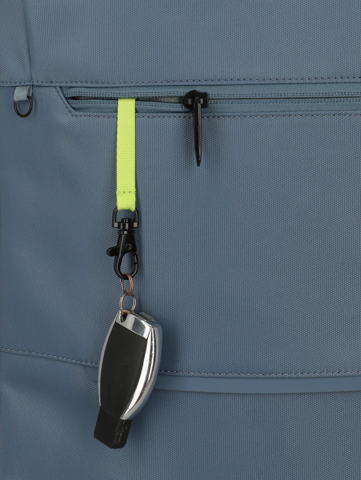 Detailansicht einer blauen Tasche mit Reißverschluss und Schlüsselanhänger an gelbem Band