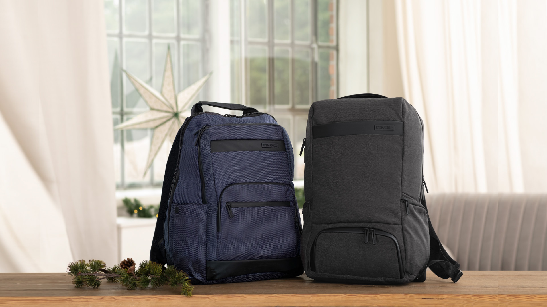 Stylische Rucksäcke in Blau und Grau mit modernem Design Zwei stilvolle Rucksäcke auf einem Tisch, einer in Blau, der andere in Grau, vor einem Fenster mit einem dekorativen Stern.