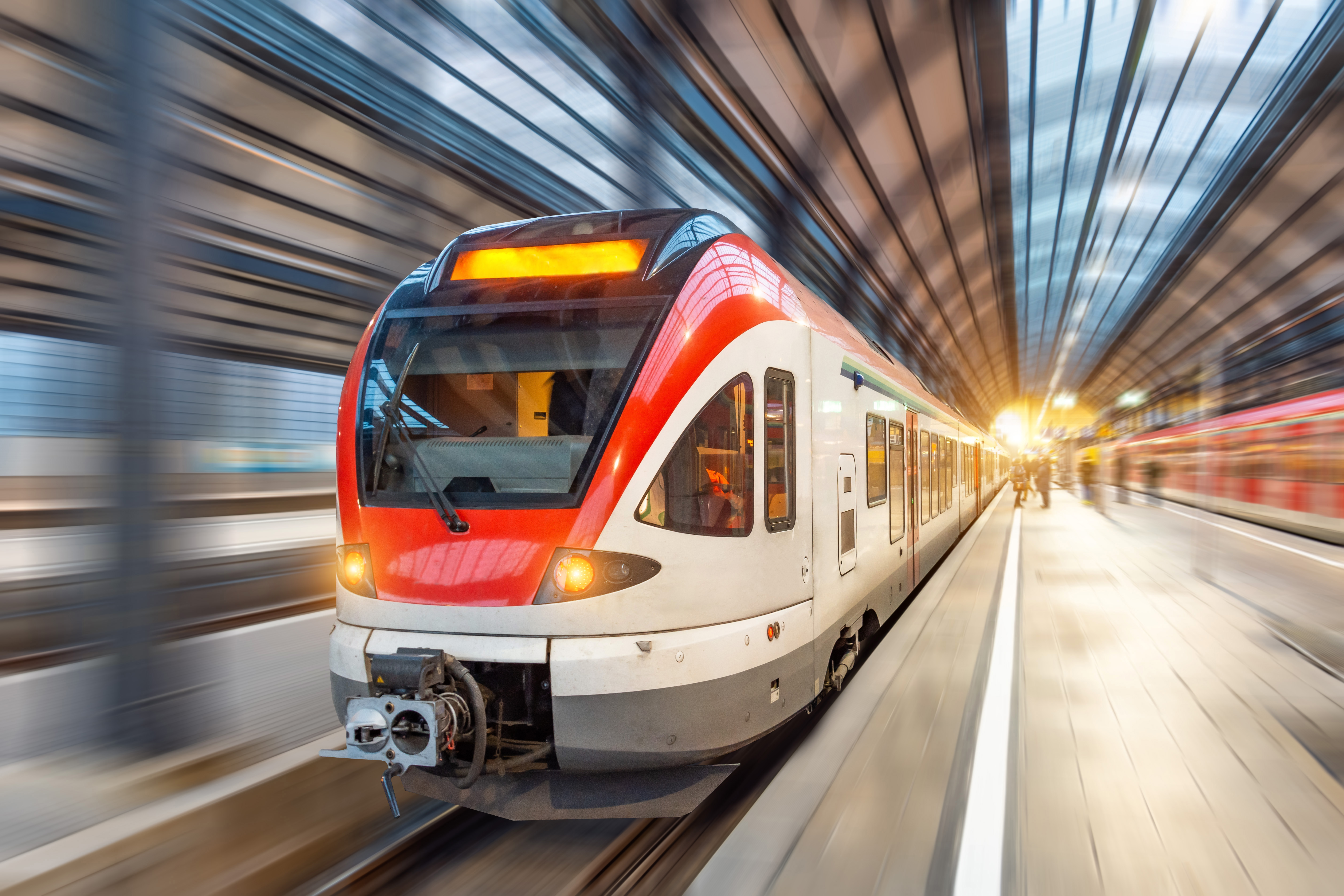 Deutsche Bahn Gepäck – das solltest du bei einer Reise mit dem Zug beachten Ein roter und weißer Zug fährt schnell durch einen modernen Bahnhof