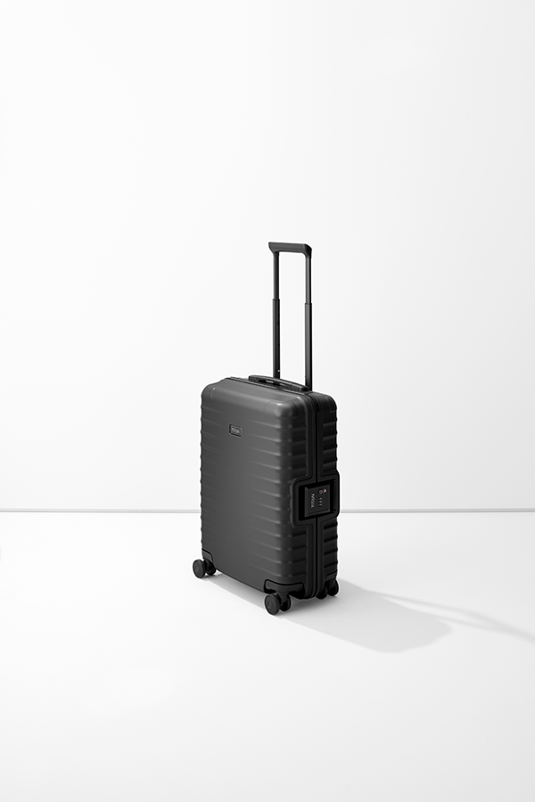 Trolley TITAN S20 nero, verticale, su una base chiara. La valigia ha una maniglia estensibile e doppie rotelle. Sul lato destro è visibile una serratura a combinazione. La superficie del carrello è leggermente scanalata.