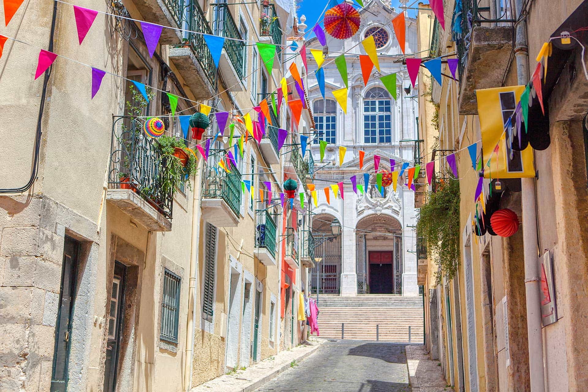 Farbenfrohe Gasse mit Wimpeln und historischen Gebäuden Eine bunte Gasse mit Wimpeln, flankiert von historischen Gebäuden im Sonnenschein.