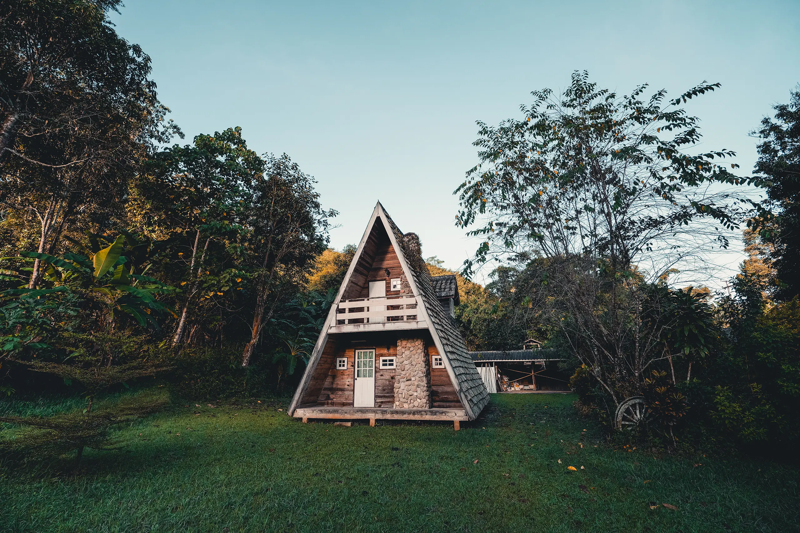 Besondere Unterkünfte Deutschland: tauche ein in einzigartige Übernachtungserlebnisse A-förmiges Holzhaus mit Steinkamin, Balkon und Holztür, umgeben von grüner Wiese und dichtem Wald