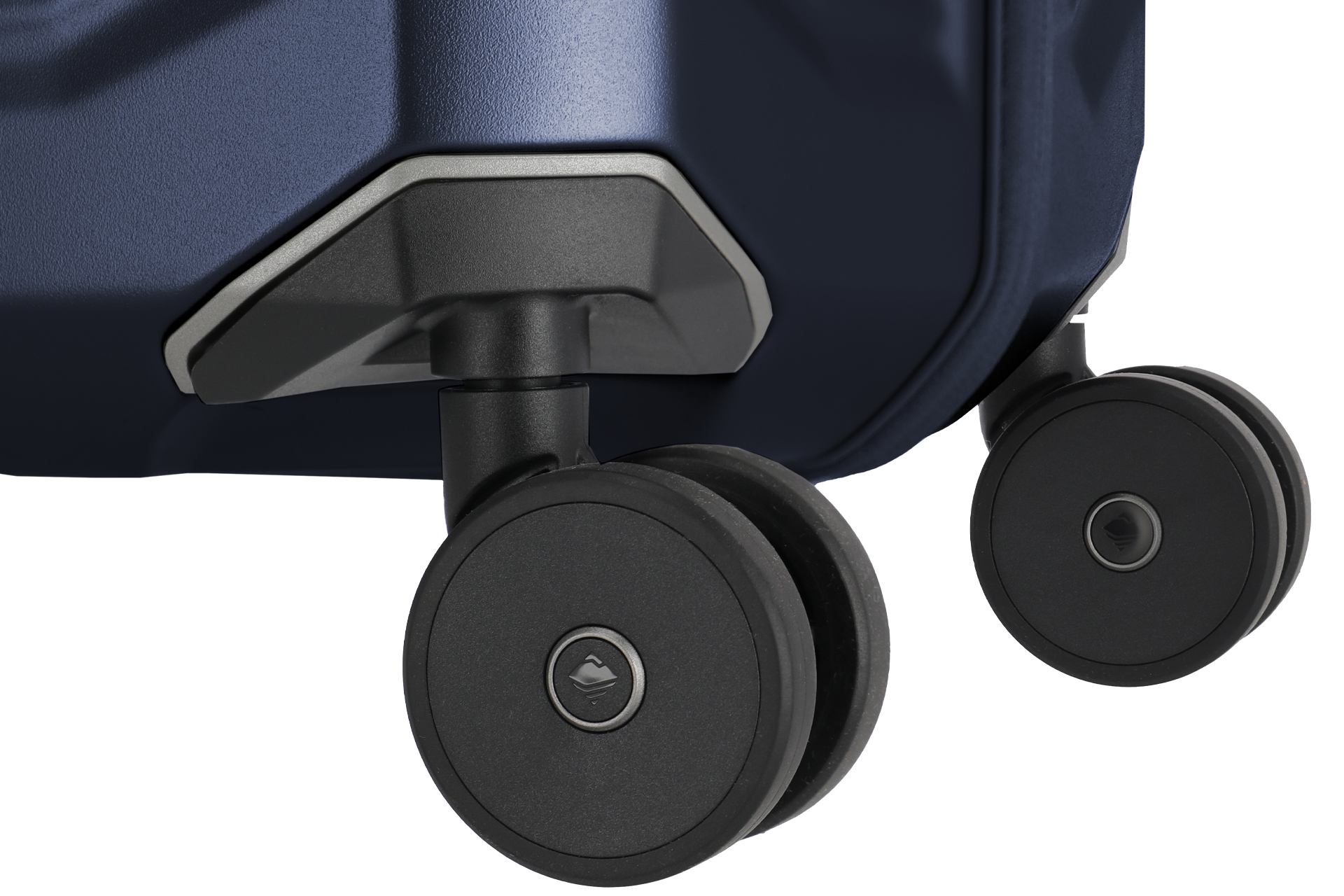 Nahaufnahme eines Koffers mit Fokus auf zwei schwarzen Rädern. Der Koffer ist dunkelblau mit grauer Verstärkung über den Rädern. Die Räder sind glatt mit dezenter Markierung in der Mitte. Der Hintergrund ist unscharf und in dunklen Tönen gehalten.