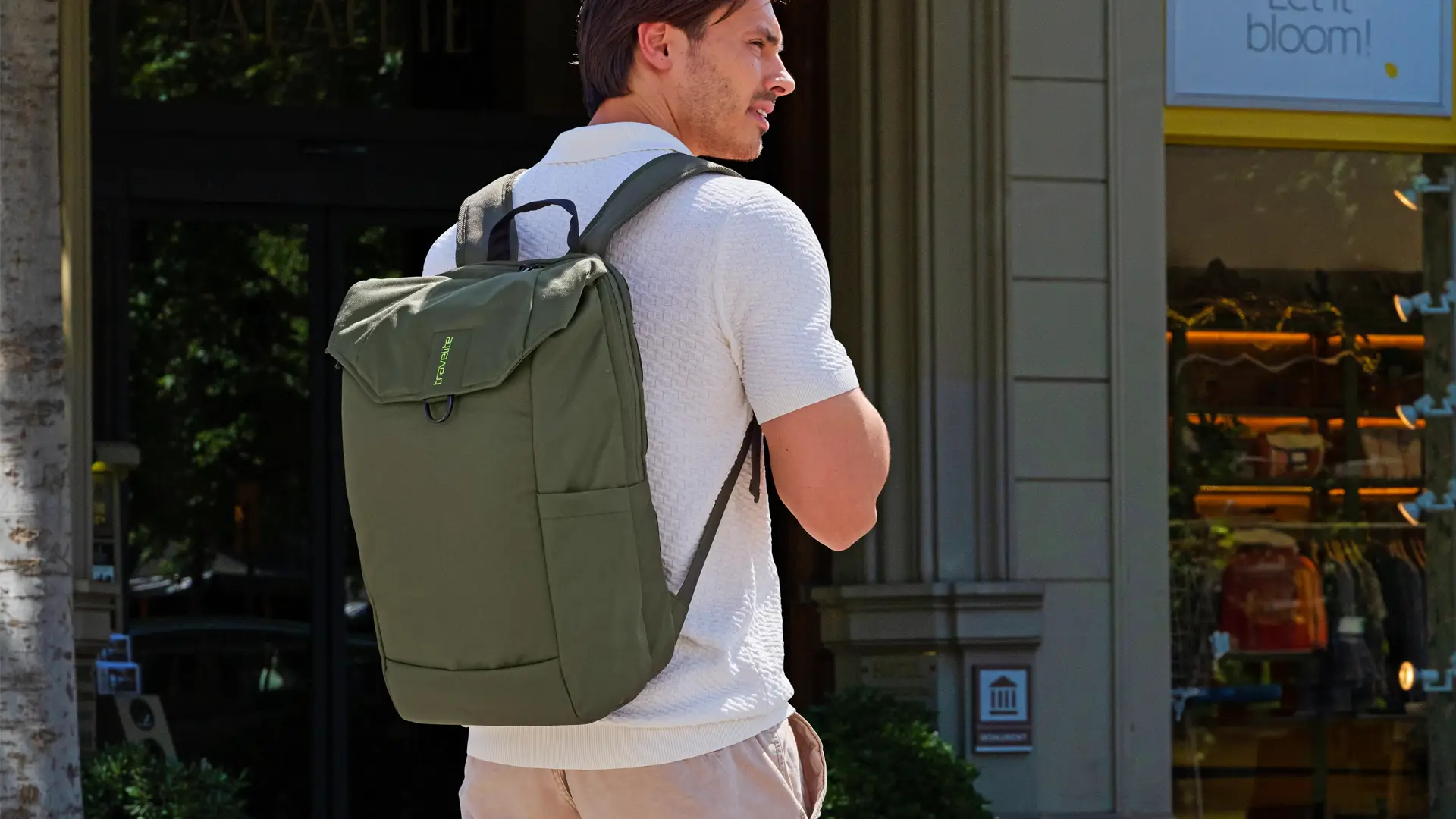 Moderner olivgrüner Rucksack von travelite – ideal für Freizeit und Alltag Junger Mann mit olivgrünem travelite Rucksack auf dem Rücken vor einem Gebäude