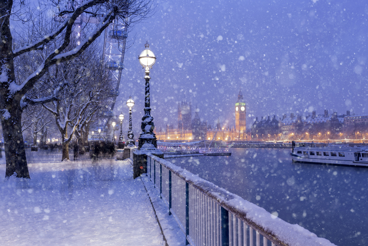 Besneeuwde promenade langs de Theems met uitzicht op de Big Ben en huizen op de achtergrond in de winter