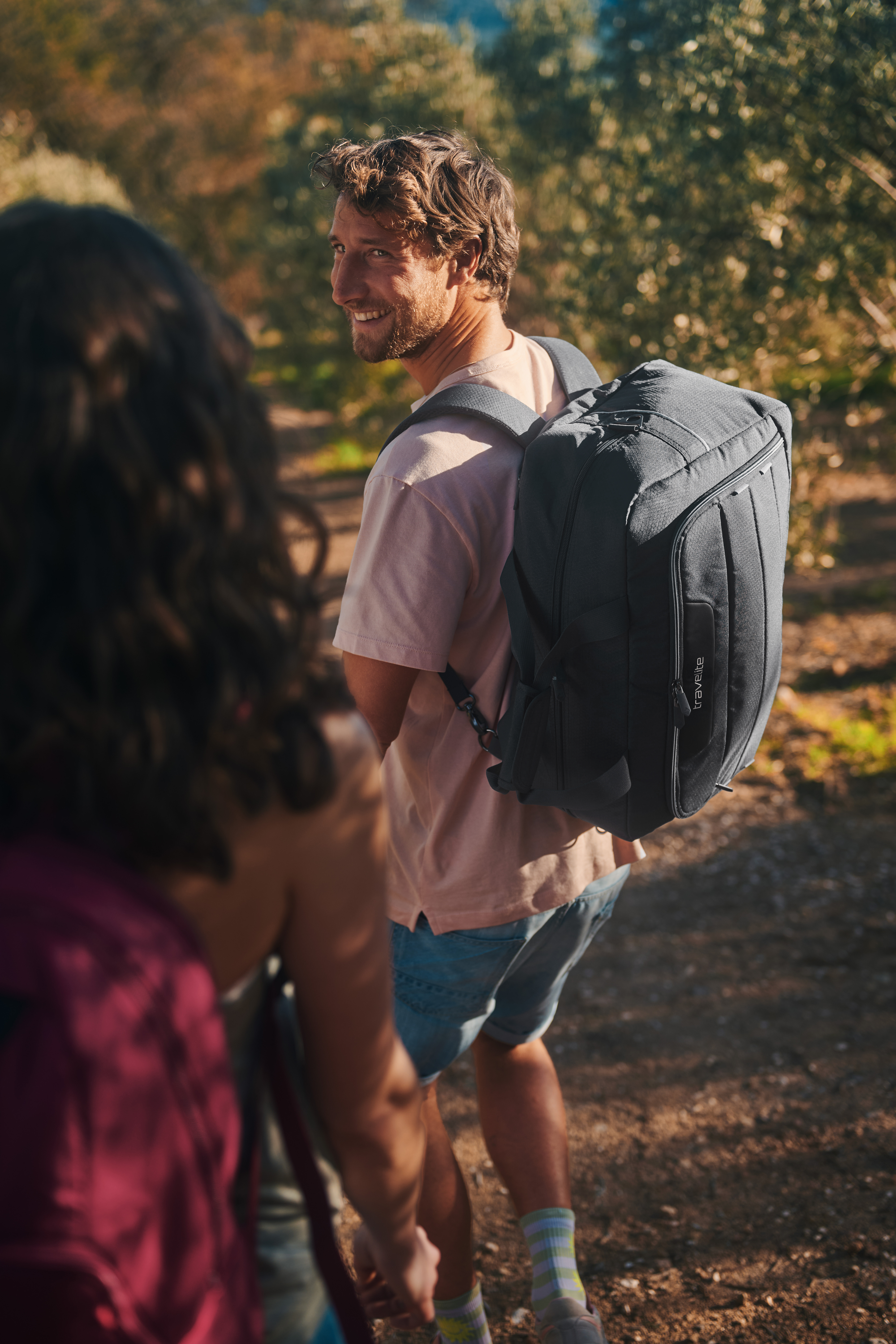 Mann mit grauem Rucksack beim Wandern in der Natur