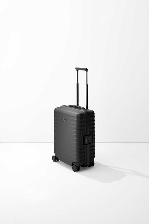Carrello verticale S23 nero di TITAN con maniglia estensibile e quattro ruote doppie su uno sfondo chiaro e neutro. Il corpo del carrello ha una struttura a coste e una serratura a combinazione integrata.