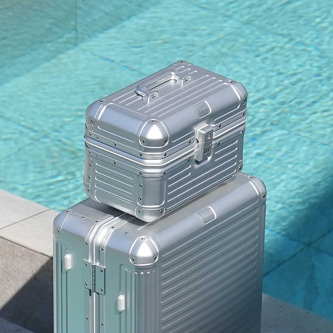 Set aus zwei silbernen Aluminiumkoffern am Poolrand Zwei silberne Aluminiumkoffer, perfekt für stilvolle Reisen, stehen am Rand eines Pools.