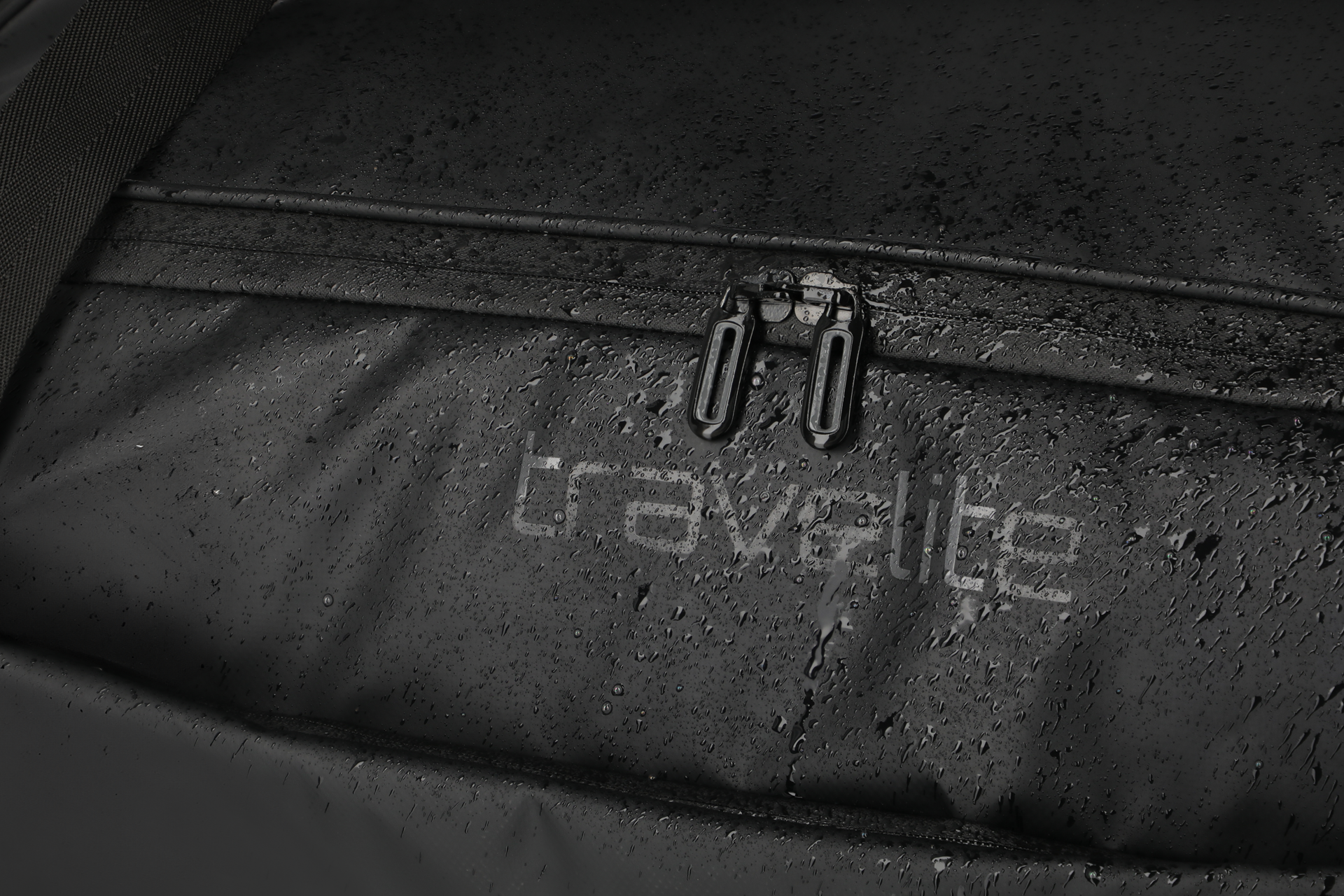 Wasserabweisender Reissverschluss in schwarz Detailbild eines Reissverschlusses mit Wassertropfen und travelite Logo