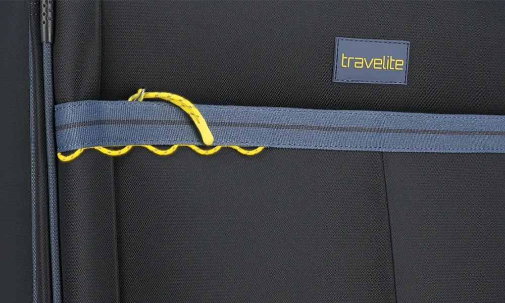 Detailansicht Koffer-Innenfach mit elastischem Spanngurt und travelite-Logo Nahaufnahme eines Kofferinnenraums mit elastischem, gelb-grauem Spanngurt und travelite-Logo auf schwarzem Stoff