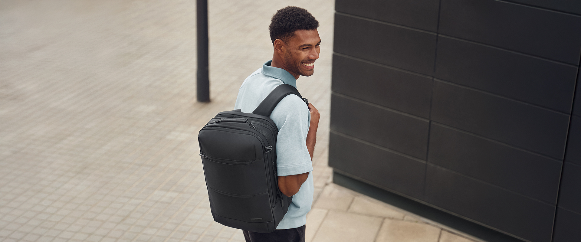 Moderner Rucksack für den Alltag - elegant und funktional Mann mit einem modernen, schwarzen Rucksack, der auf der Straße lächelnd geht