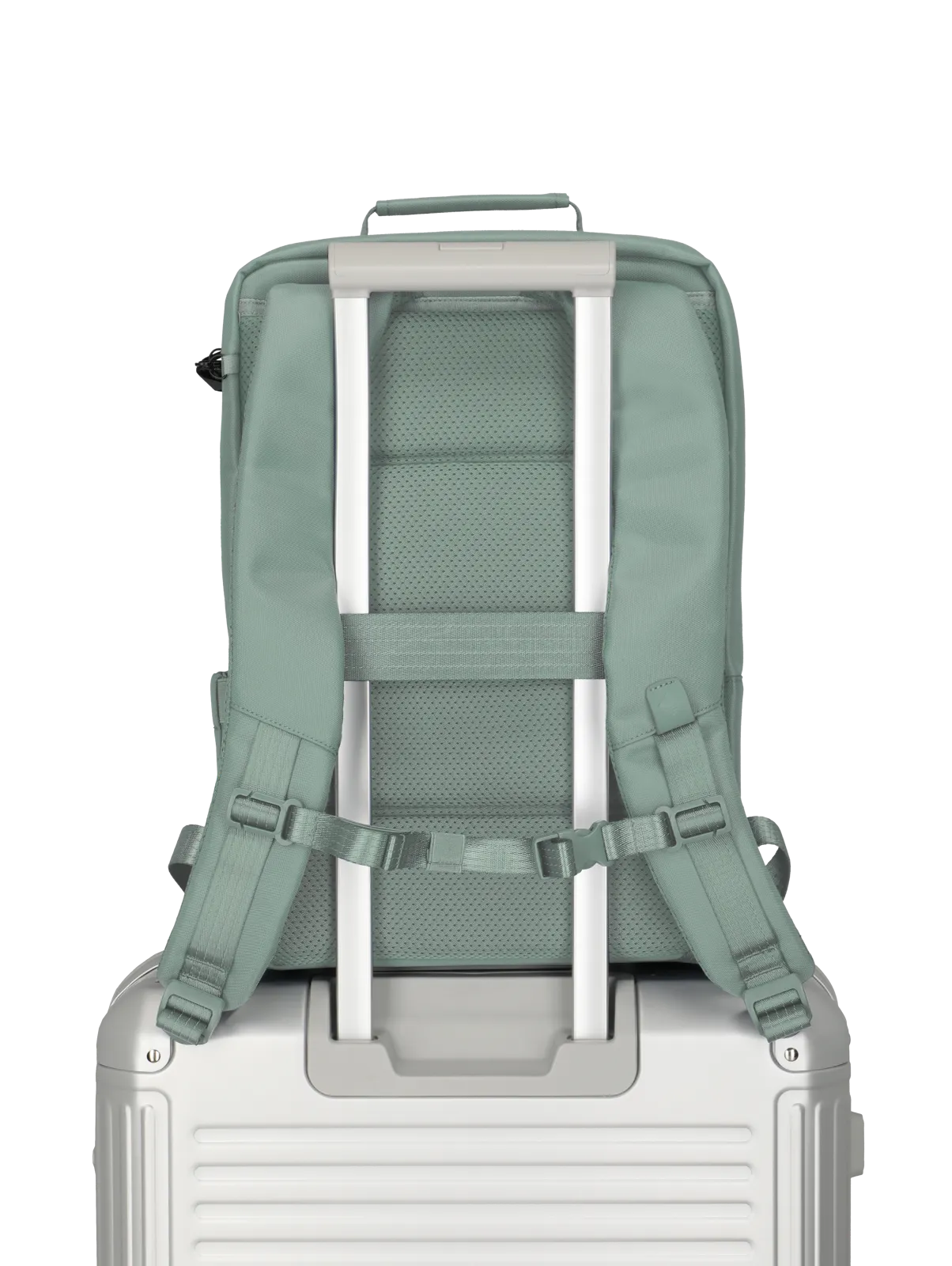 Grüner Rucksack mit zwei Trägern auf silbernem Reisekoffer mit Teleskopgriff