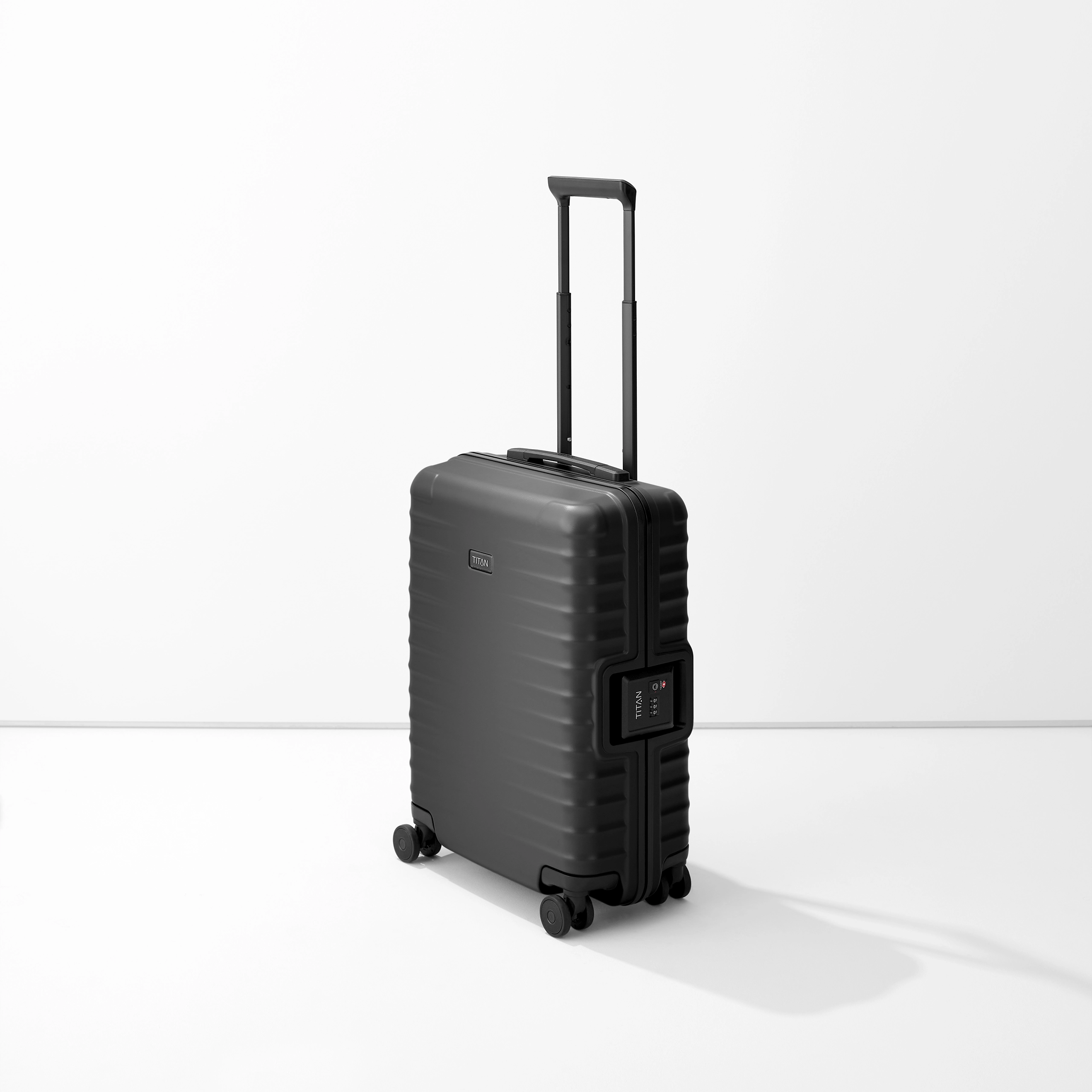 Trolley TITAN S20 nero, verticale, su una base chiara. La valigia ha una maniglia estensibile e doppie rotelle. Sul lato destro è visibile una serratura a combinazione. La superficie del carrello è leggermente scanalata.