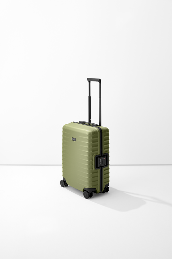 Il trolley S23 di TITAN è di colore verde oliva su sfondo bianco. La valigia ha una maniglia nera e quattro rotelle doppie nere. Sul lato è applicata una serratura a combinazione ed è riconoscibile il logo TITAN.