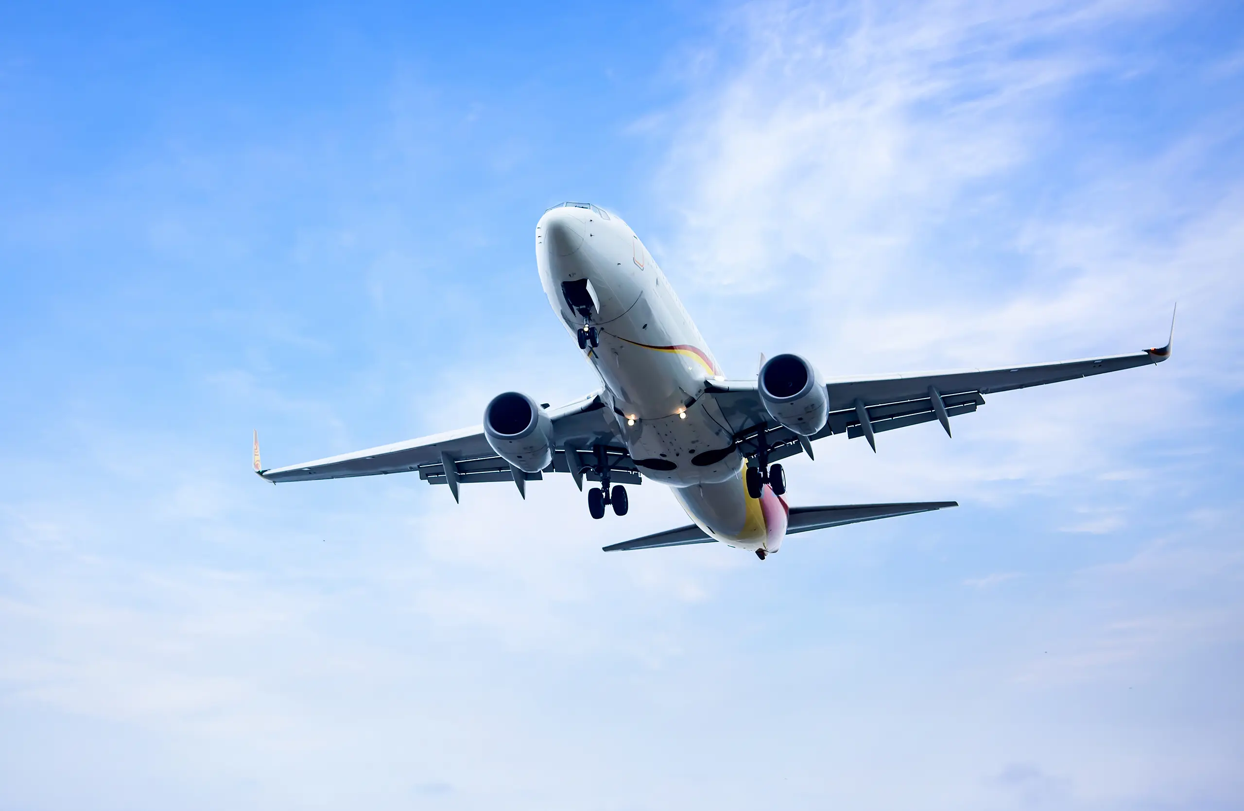 Das erste Mal fliegen: Mit unseren Tipps meisterst du deinen ersten Flug Ein Passagierflugzeug im Landeanflug mit ausgefahrenem Fahrwerk vor blauem Himmel