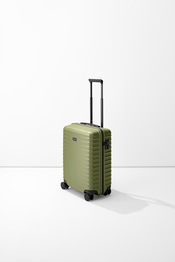 Un trolley verde TITAN S23 poggia su una base bianca. La valigia ha una maniglia nera, che si estrae, e quattro ruote nere. Sul lato è presente una serratura a combinazione.