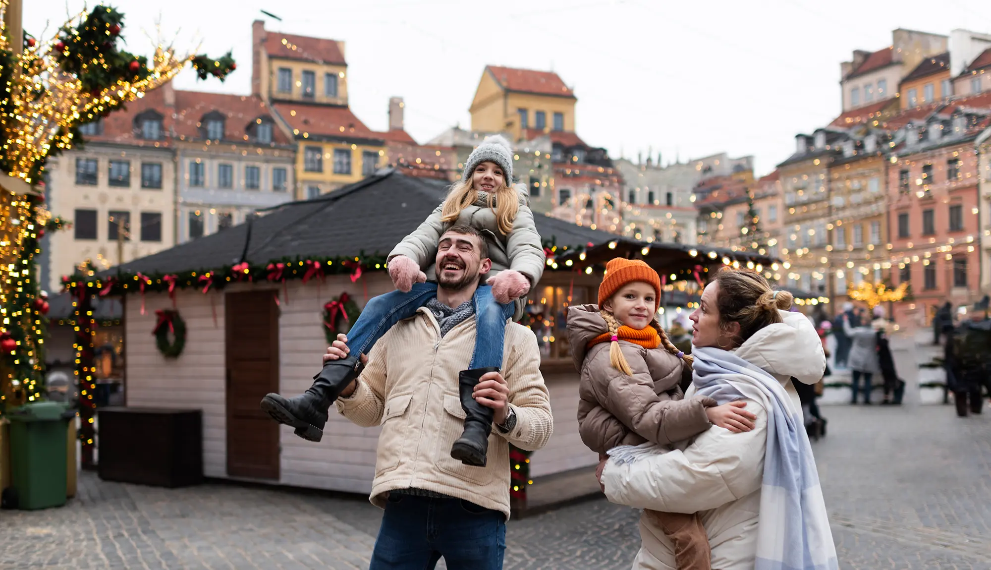 Städtetrip Dezember: Entdecke den Zauber der schönsten Weihnachtsmärkte Eine Familie steht vor einem weihnachtlich geschmuecktem Haus