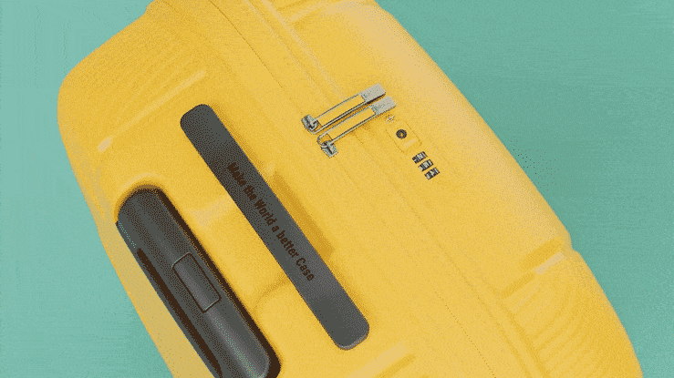 Close-up of a yellow hard case with integrated combination lock, black handle and graphic with 'Make the World a Better Case' on a turquoise background.